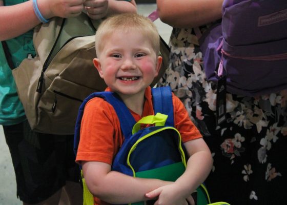 little boy clutching book bag